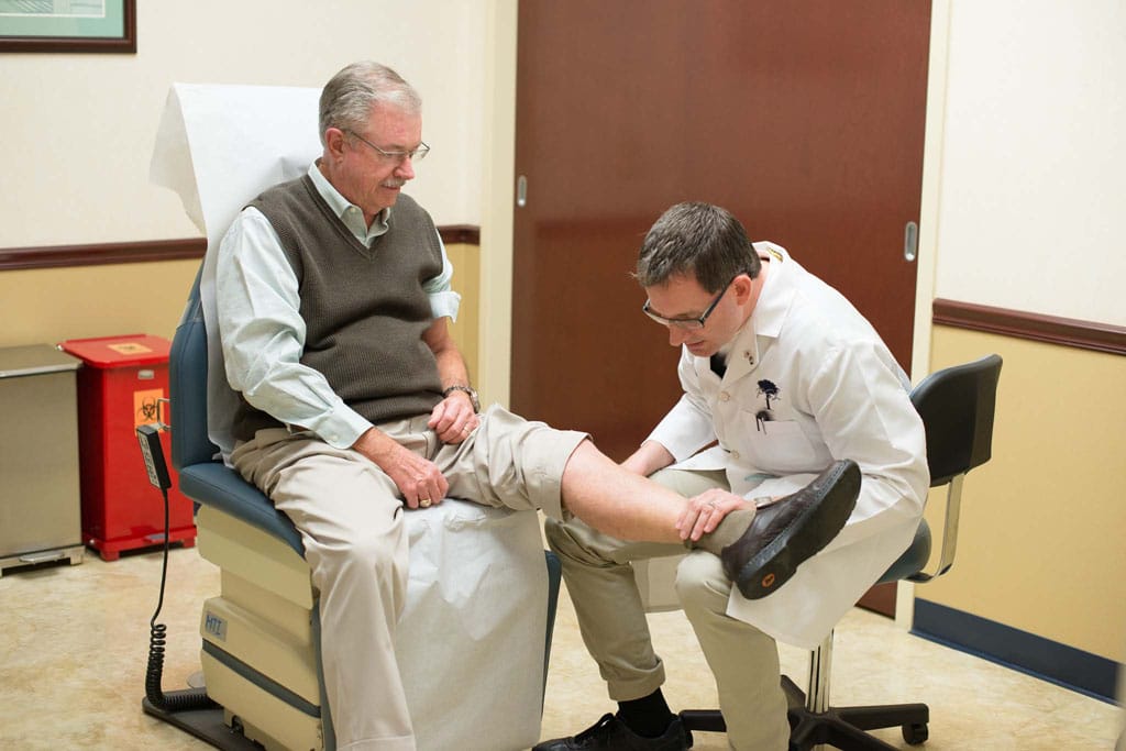 Doctor inspecting elderly mans shin