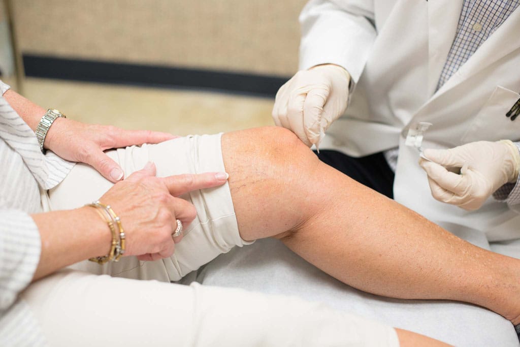 Doctor applying bandaid to woman's knee