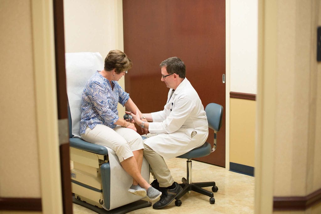 Doctor performing skin inspection on back of woman's arm