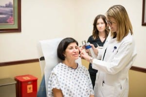 Doctor performing facial treatment to patient in chair
