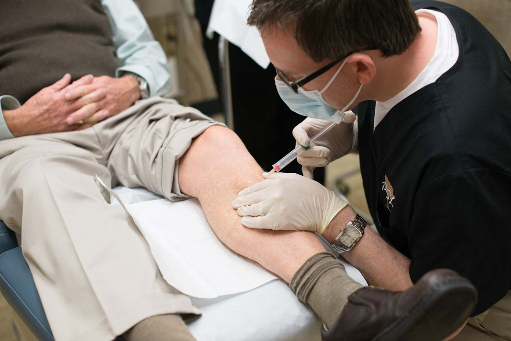 Doctor applying injection to patients leg